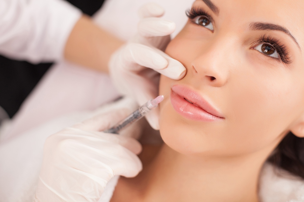 A person is receiving a cosmetic lip injection from a professional wearing white gloves at a renowned medical spa in Reno, Nevada.