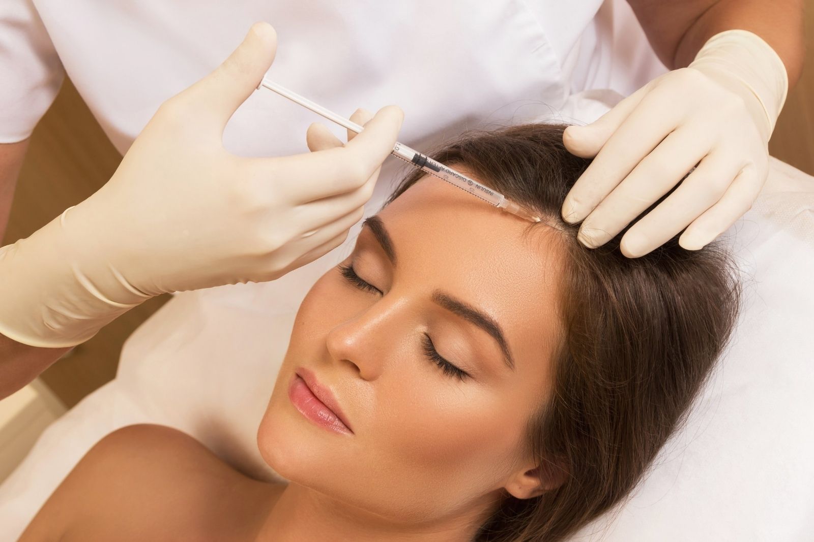 At a renowned medical spa in Reno, Nevada, a person receives a cosmetic injection in the forehead area from a professional wearing gloves.