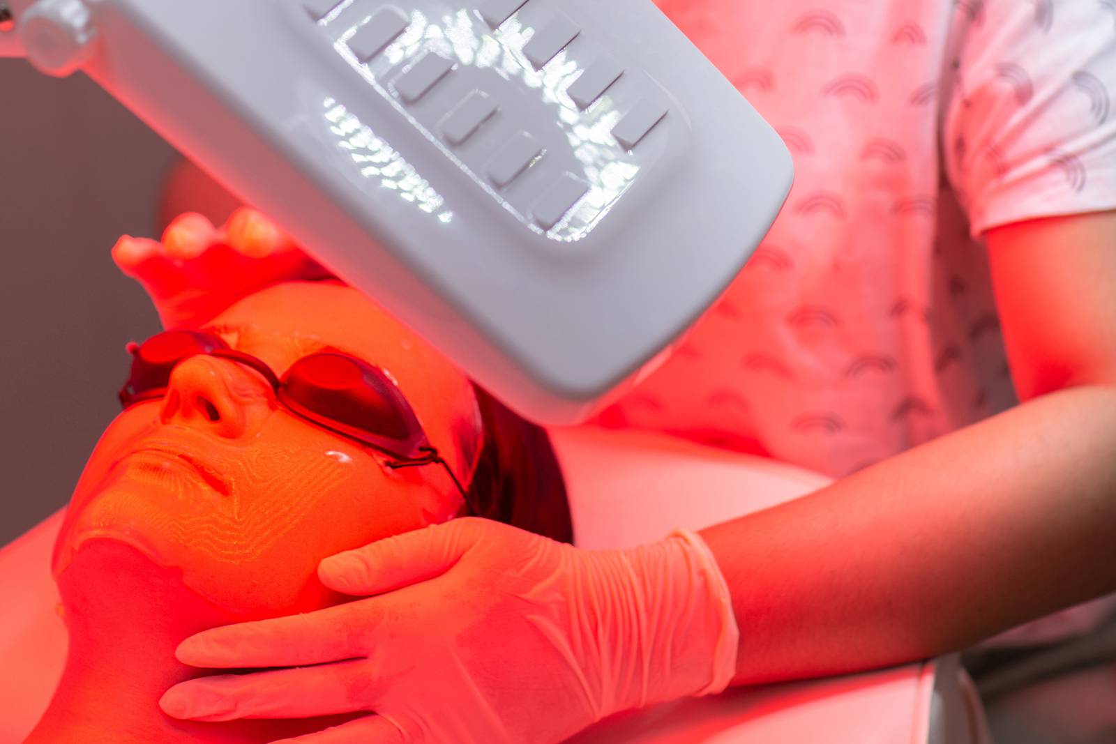 Young woman having red LED light facial therapy treatment in beauty salon