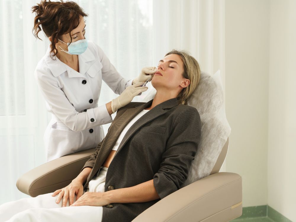 Aesthetician performing a facial treatment on a relaxed woman in a clinic.