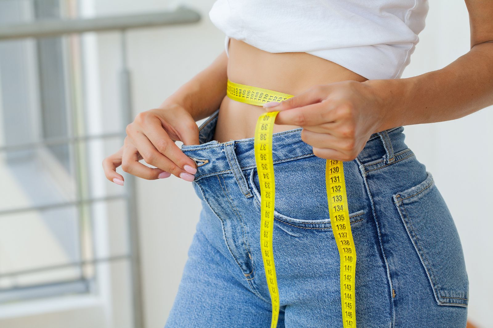 Woman measuring her waistline showing weight loss.