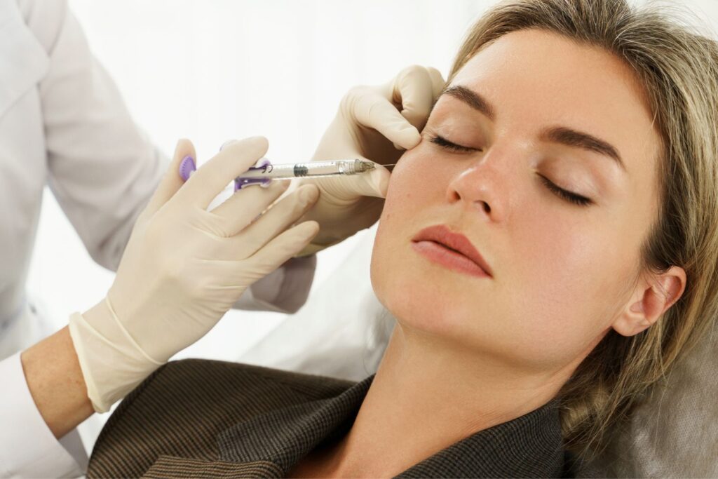 A person receiving an injection in the face from a gloved medical professional, exploring types of dermal fillers to achieve desired aesthetic results.