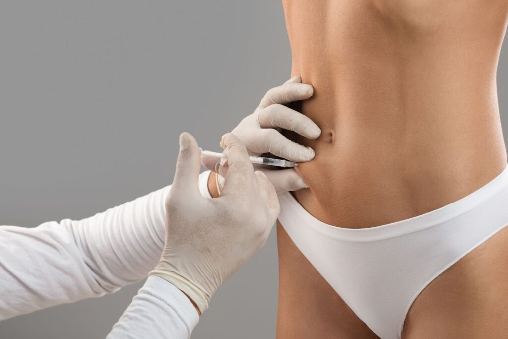 A person wearing gloves injects a syringe of Zepbound weight loss injections into the lower abdomen of a woman wearing white underwear.