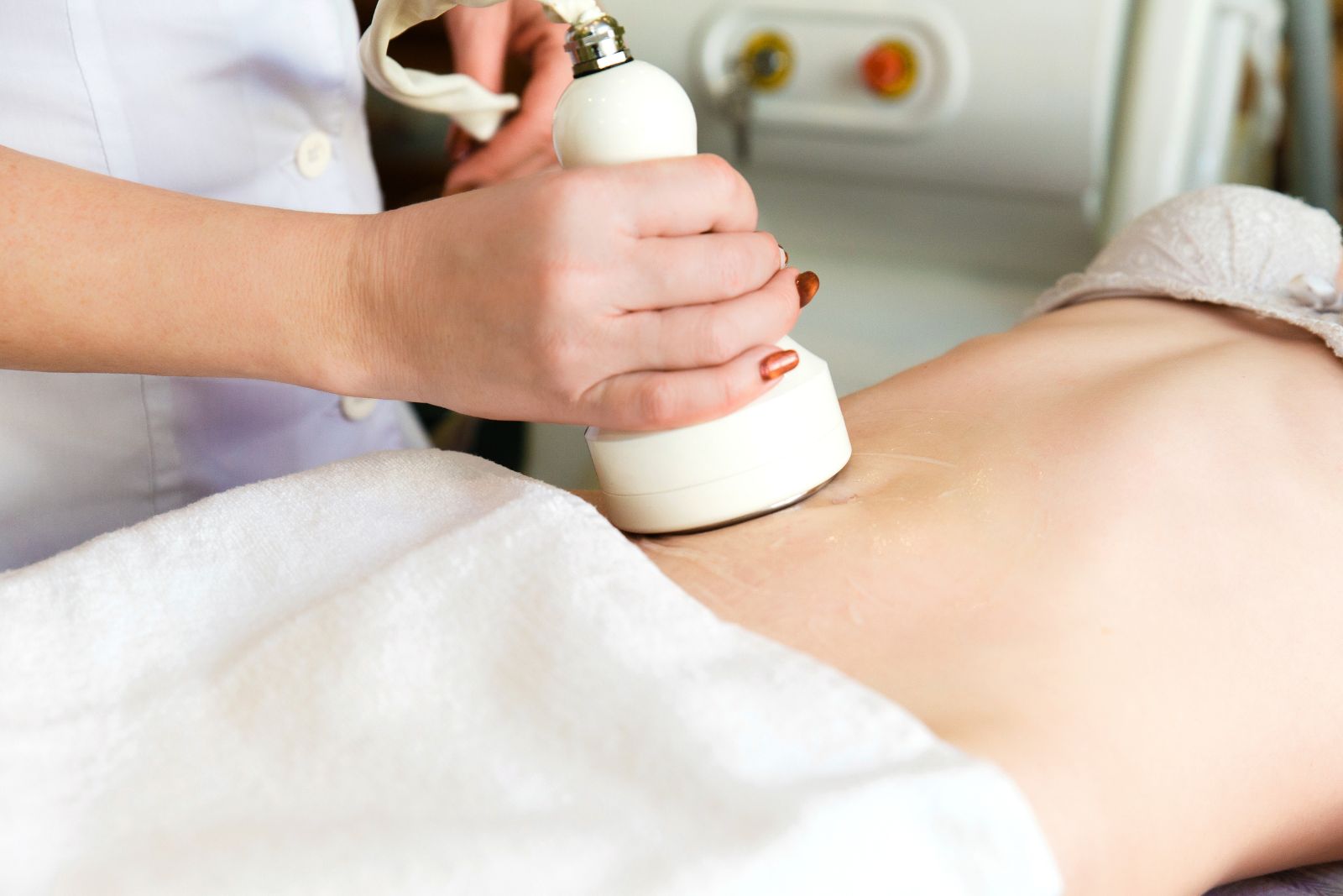 A person undergoes an Ultrashape Fat Reduction body treatment as a technician uses a handheld device on their abdomen in a clinical setting in Reno.