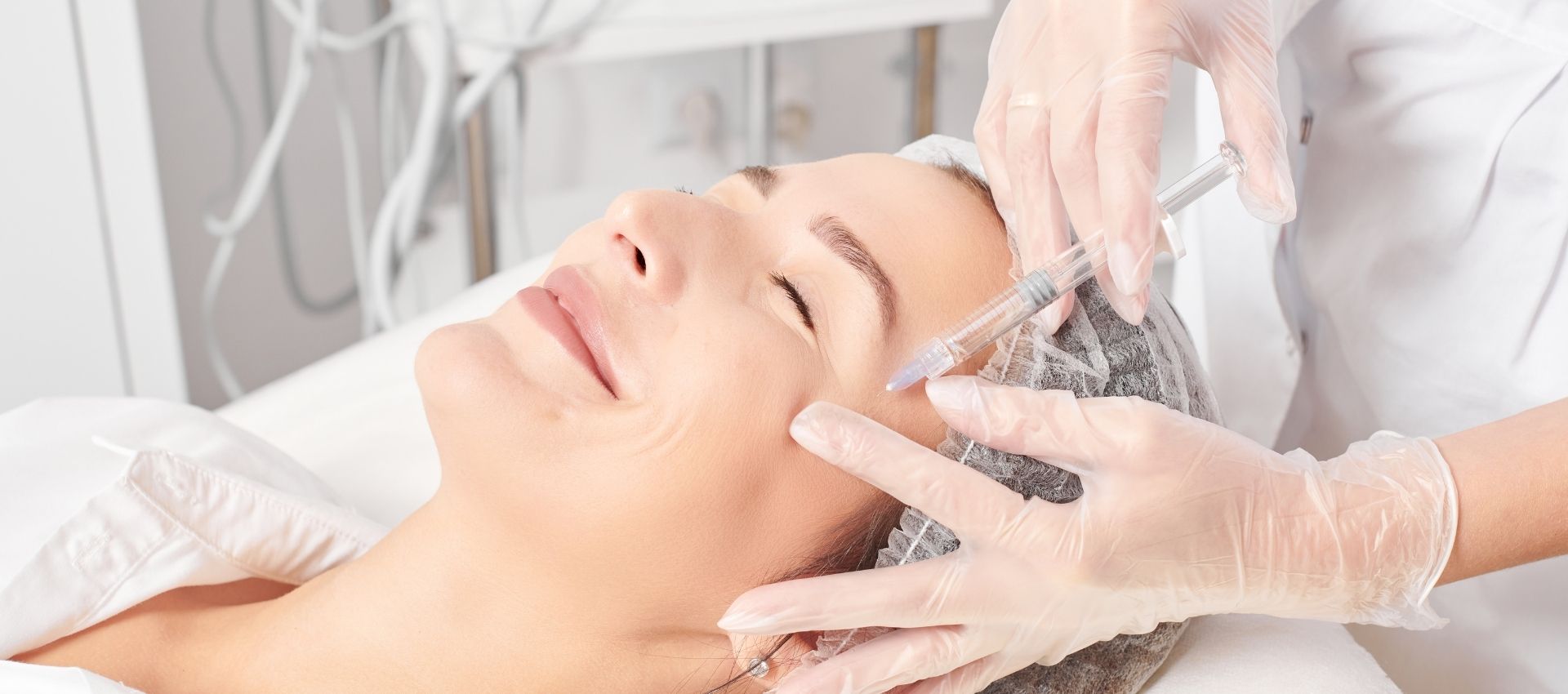 A person lying on a medical bed in Reno receives Xeomin injections near the eye from a gloved practitioner.