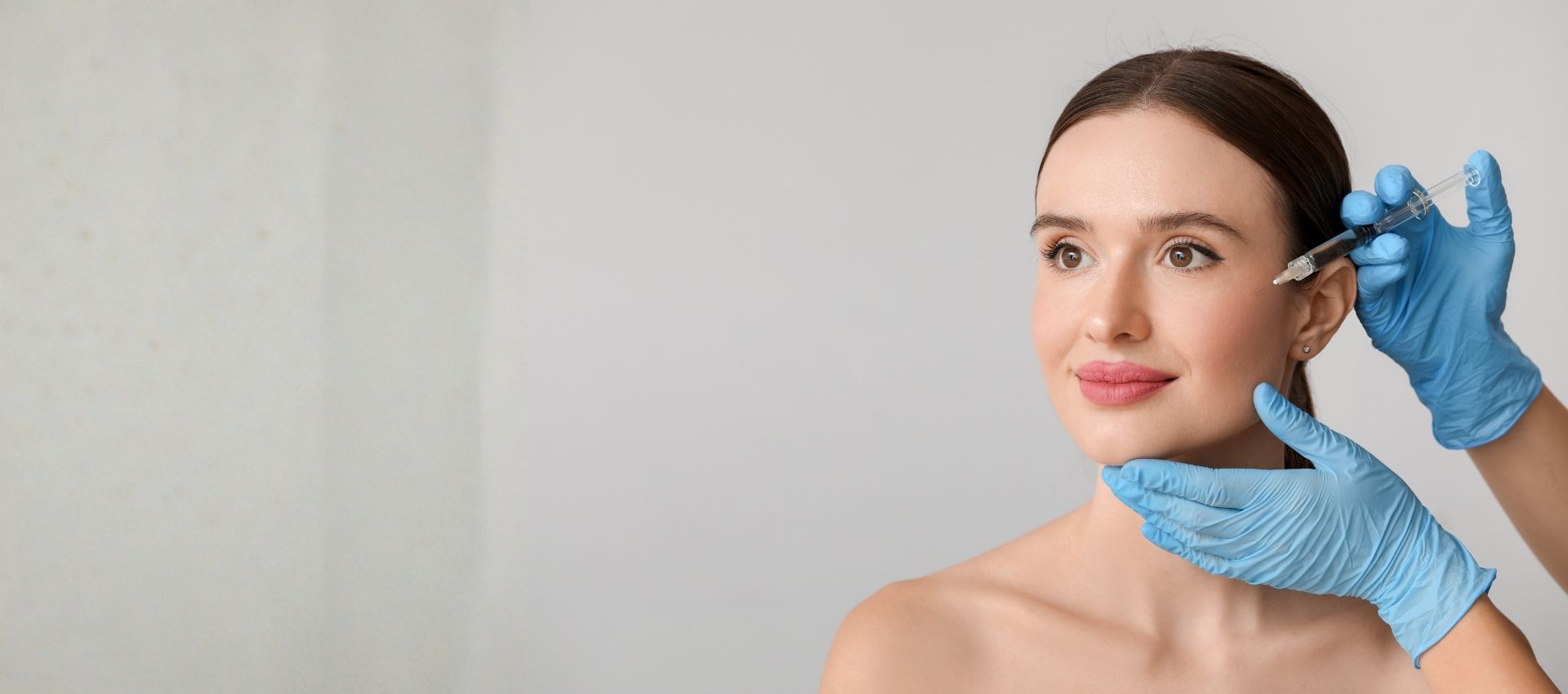 A woman receiving a dermal filler injection for cheek enhancement and facial volume restoration.