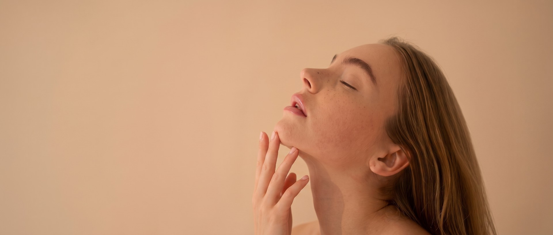 Side profile of a woman touching her defined chin and jawline after a dermal filler treatment.