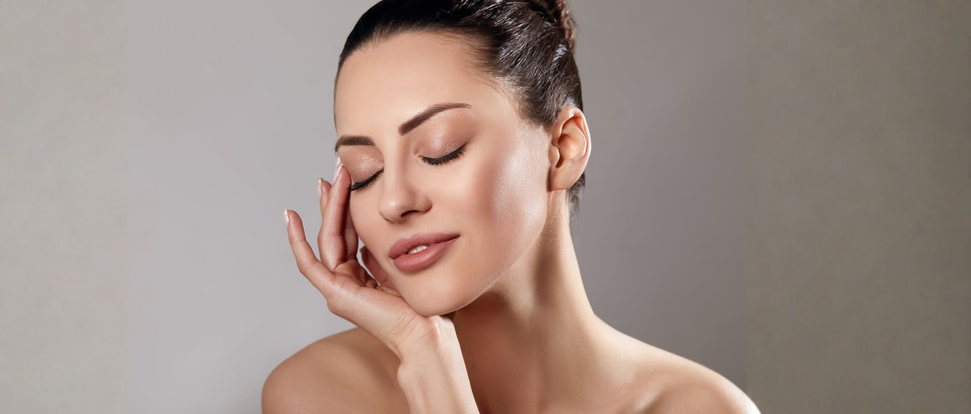 Woman with closed eyes touching her clear, glowing cheek after laser skin resurfacing facial rejuvenation.