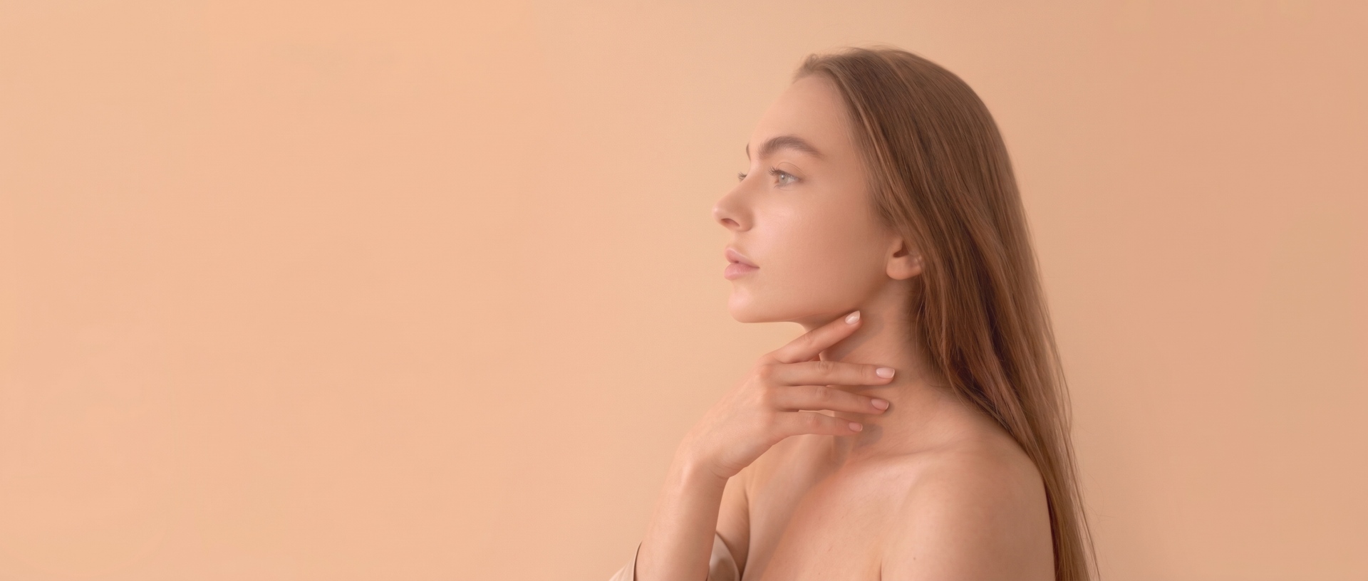 Profile view of a woman gently touching her defined jawline and chin after an aesthetic dermal filler treatment.